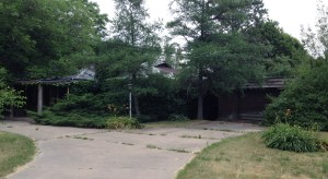 June 30, 2012: A tarp covers the roof and the front of the house is overgrown.